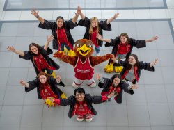 Graduates pose with Rocky in a circle.